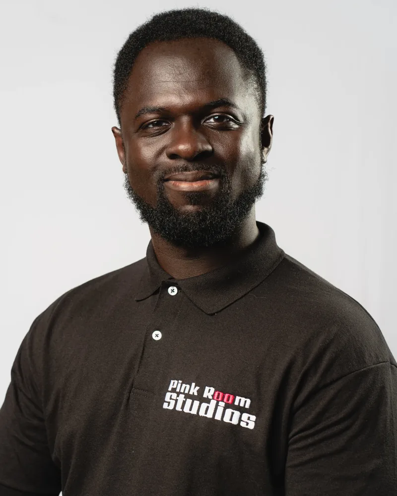 Portrait of William Twum, smiling, in a black PinkRoom Studios polo.